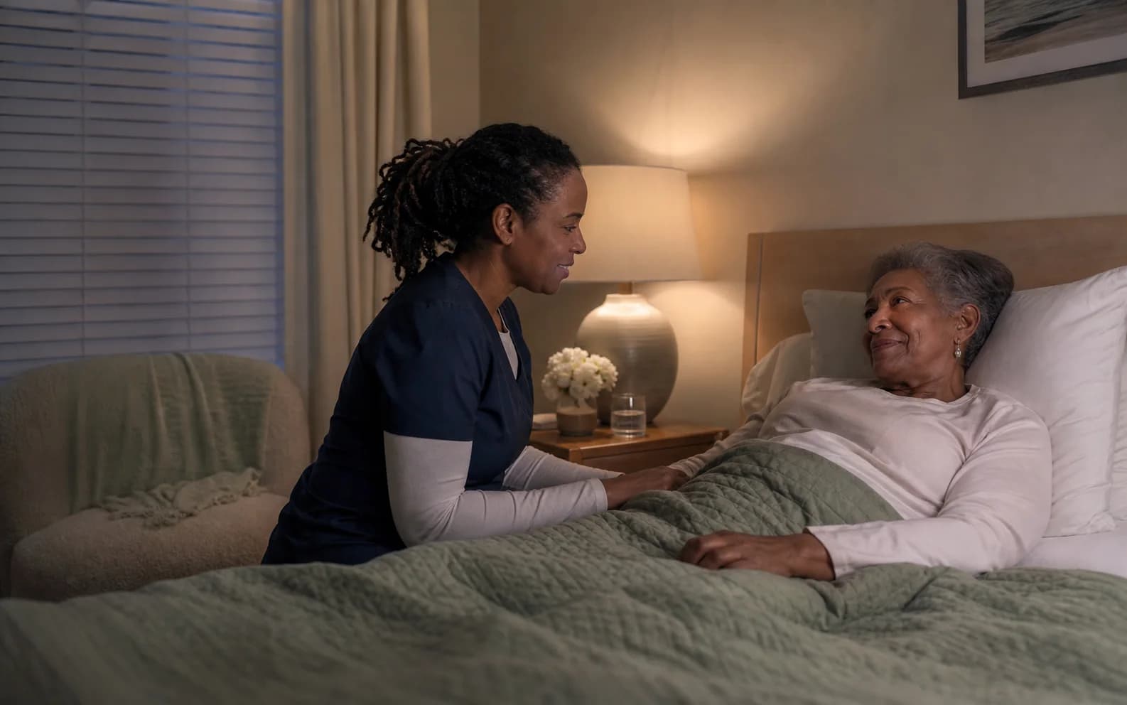 An overnight caregiver checking that an older adult is comfortable and safe at home